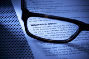 Image of an insurance policy with eyeglasses magnifying the text, representing the intense care placed on insurance claim and coverage issues for defendants and plaintiffs by Charleston, WV insurance attorney M. Andrew Brison at The Law Office of M. Andrew Brison, PLLC.