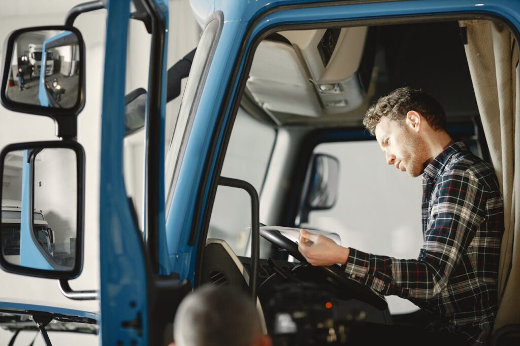 A man sits in a tractor-trailer reading paperwork, representing the role of complaint hiring in WV trucking accident defense.